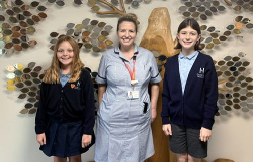 Two ten year old girls visited St Helena Hospice to write an article for the newspaper, here they are pictured with nurse Holly