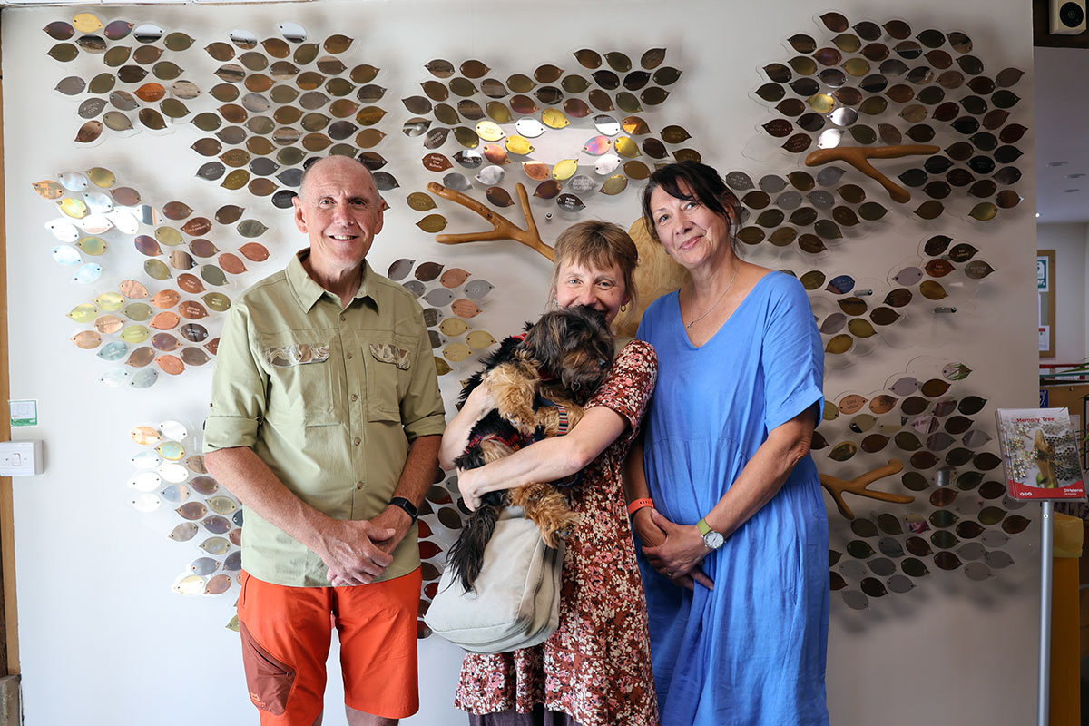 A Family And Their Dog Standing In Front Of The Memory Tree 1200X800